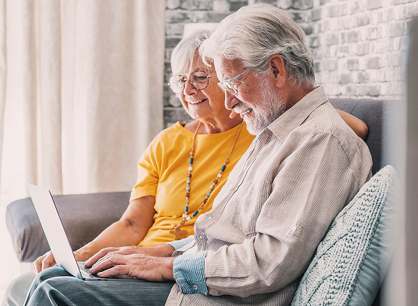Two people sitting on a couch looking at laptop